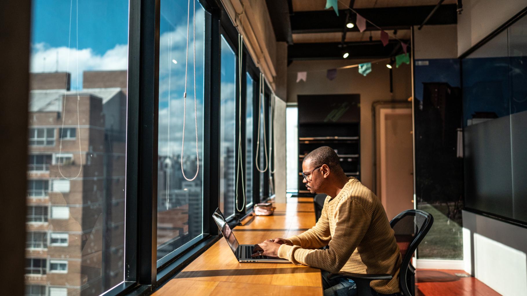 Man on laptop in front of an office window