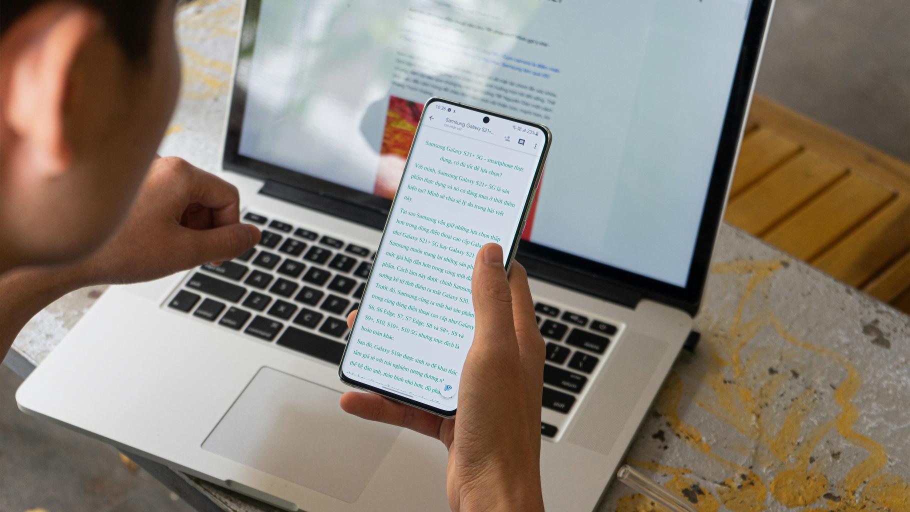 Person working on computer and viewing phone
